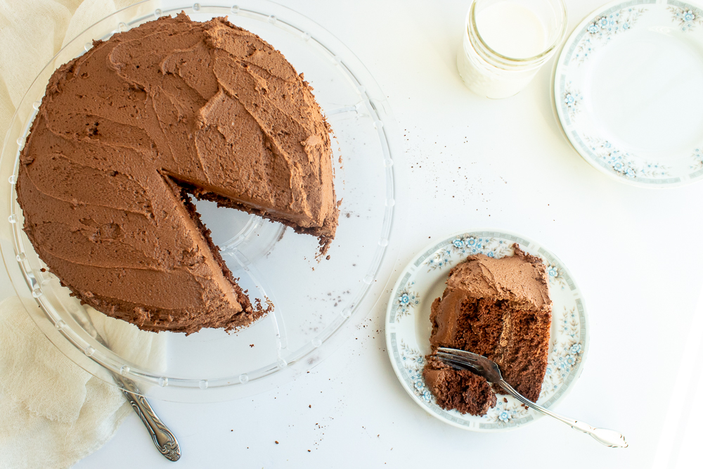 chocolate buttercream frosting on chocolate layer cake overhead shot with slice on plate.