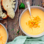 Broccoli cheddar soup overhead shot in a bowl with shredded cheese on top.
