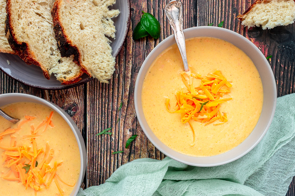 Broccoli cheddar soup overhead shot in 2 bowls with shredded cheese on top and spoons.