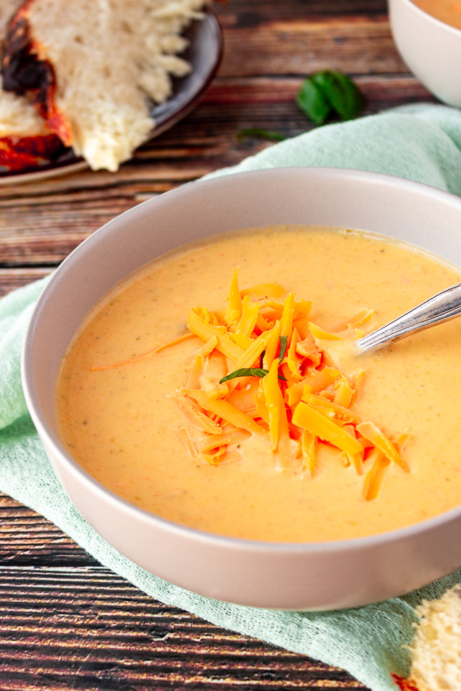 Broccoli cheddar soup angled shot in a bowl with shredded cheese on top.