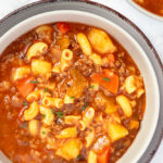 Overhead shot of Hamburger soup in bowl over plate on marble surface.