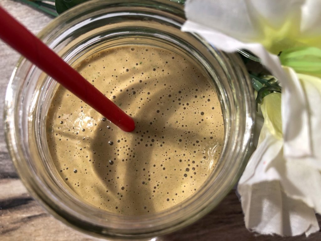 chocolate protein green smoothie with red straw and artificial flowers