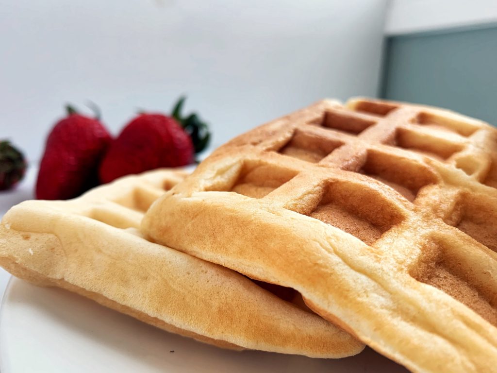 soft & fluffy waffles stacked on plate with strawberries