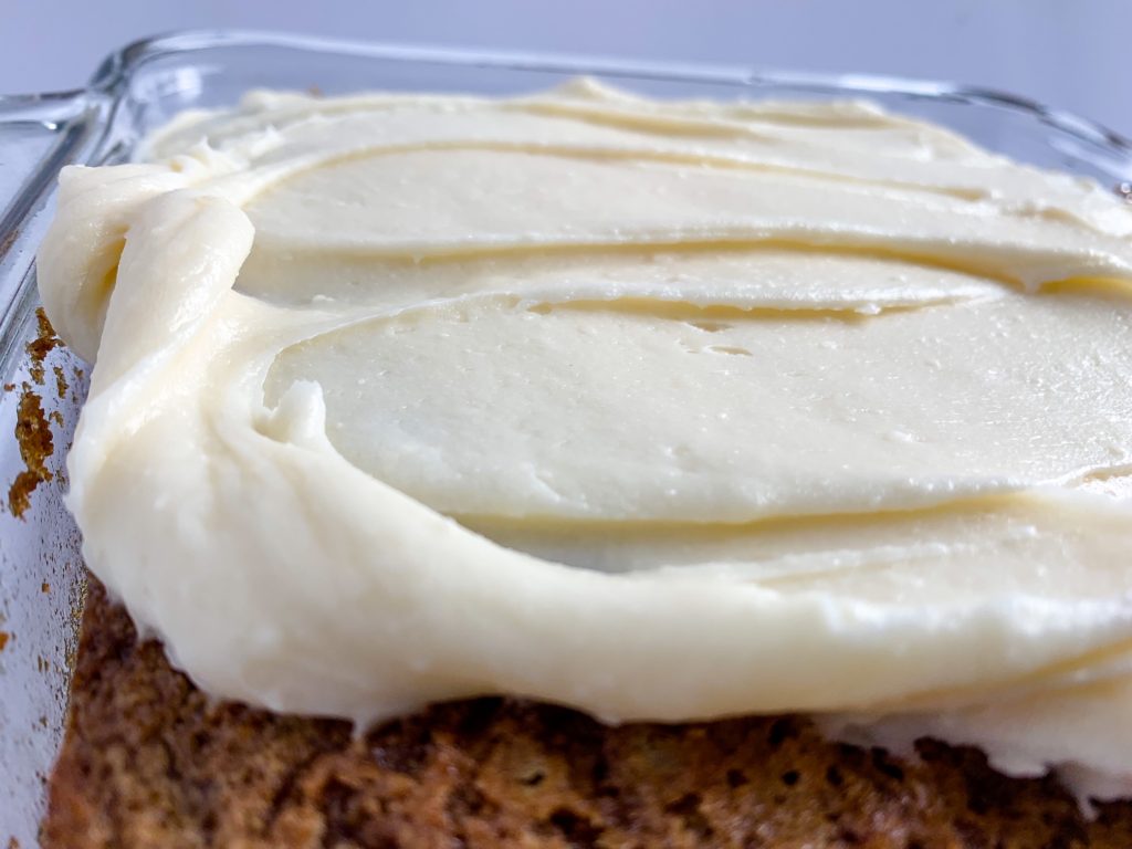 cream cheese frosting spread on carrot cake