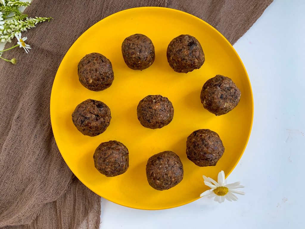 peanut butter date balls on yellow plate with a daisy