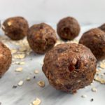 side view of peanut butter date balls on marble backdrop