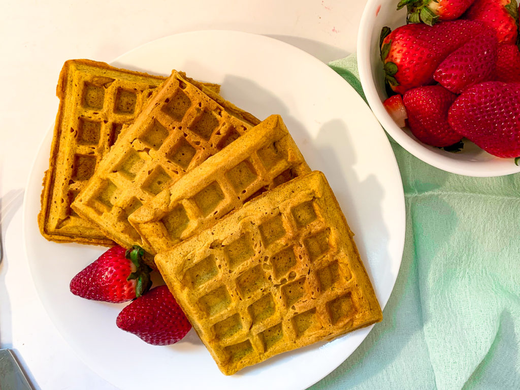 Pumpkin Spice Waffles on plate with strawberries overhead shot.