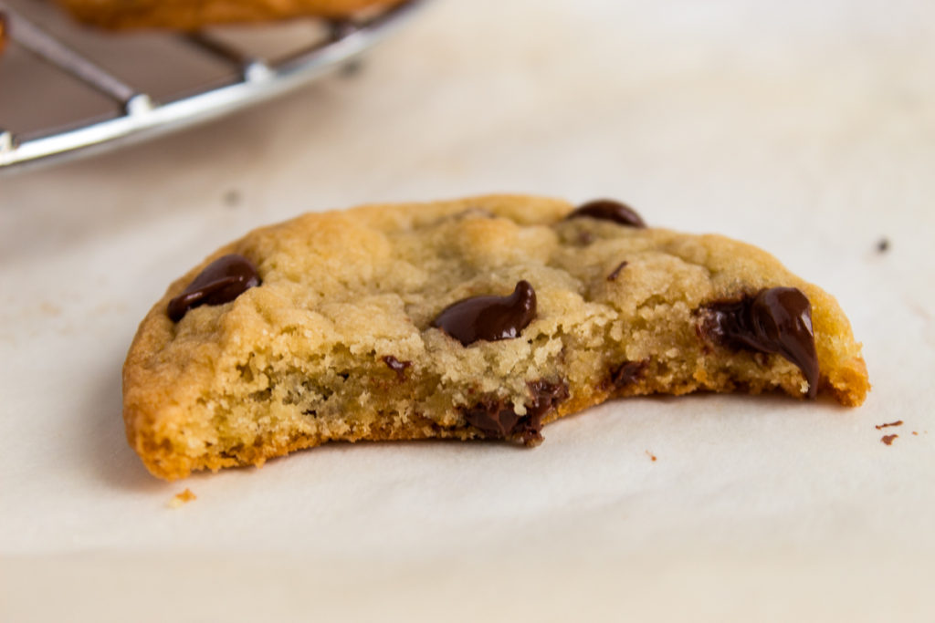 Chocolate chip cookie beside wire rack half eaten.