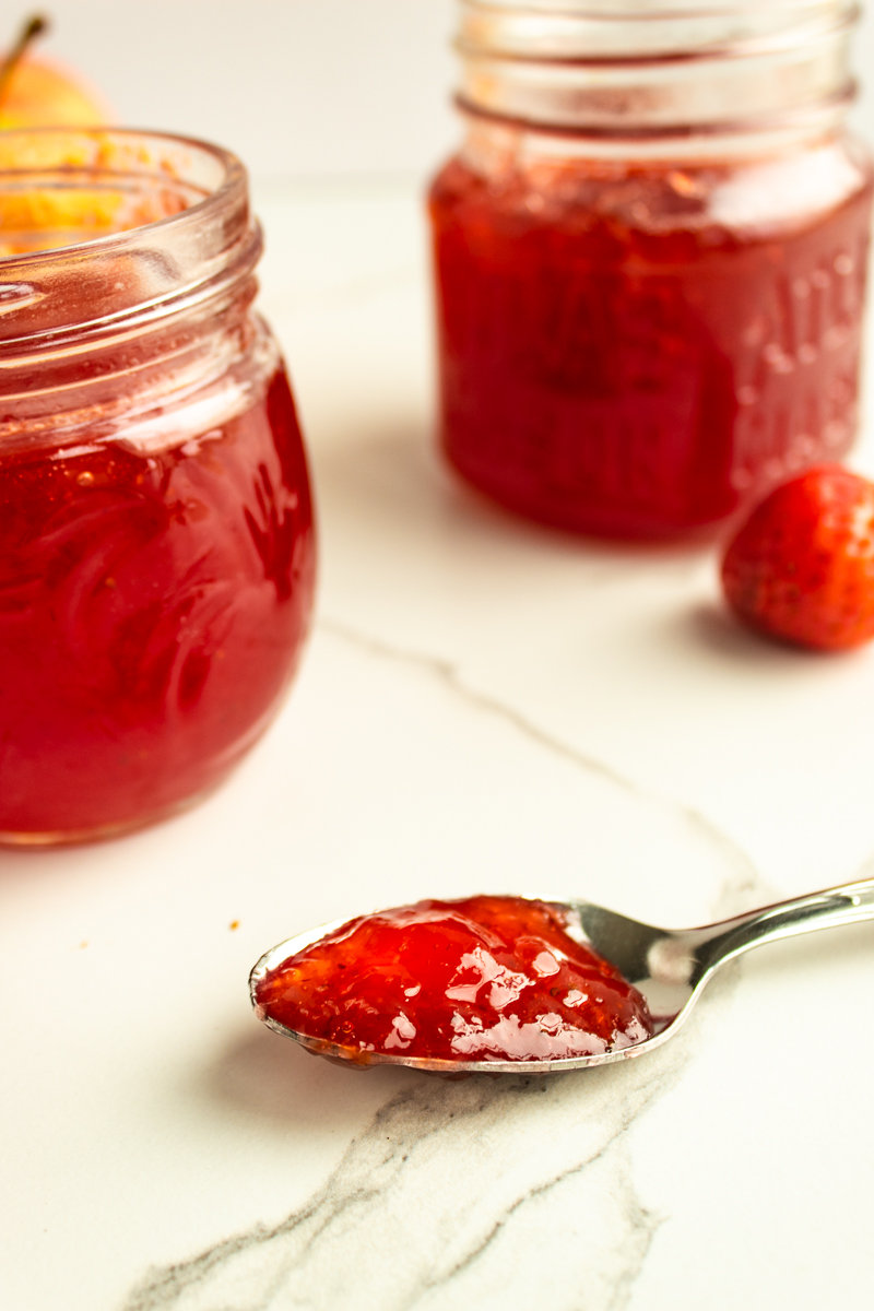 apple strawberry jam with spoonful on marble tile