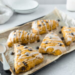 Angled shot of pumpkin chocolate chip scones on parchment lined pan.