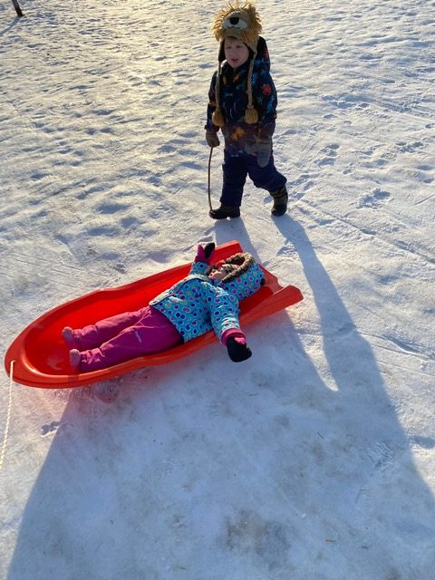 Fall 2020 at a glance: William walking on the snow, Sydney riding on the sled.