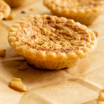 Super Easy Butter Tarts on brown paper bag with walnut pieces.