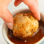 Chicken ball being dipped in bowl of sweet an sour sauce