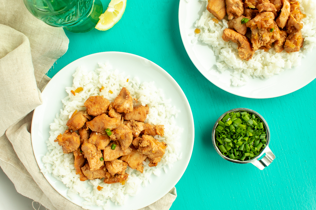 Sweet and sour chicken served over rice on plates overhead shot.