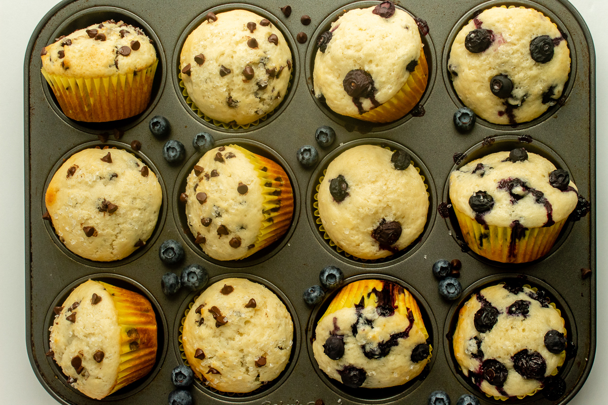 white muffins half with blueberries and half with mini chocolate chips in baking pan overhead shot