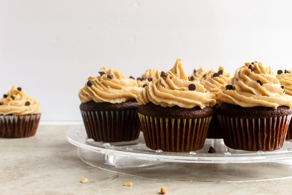 Moist Chocolate cupcakes straight on shot with peanut butter frosting on clear stand.