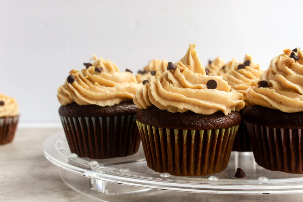 Moist Chocolate cupcakes straight on shot with peanut butter frosting on clear stand.