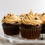 Moist Chocolate cupcakes straight on shot with peanut butter frosting on clear stand.