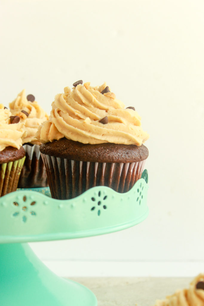 Moist Chocolate cupcakes with peanut butter frosting straight on shot on blue dessert stand