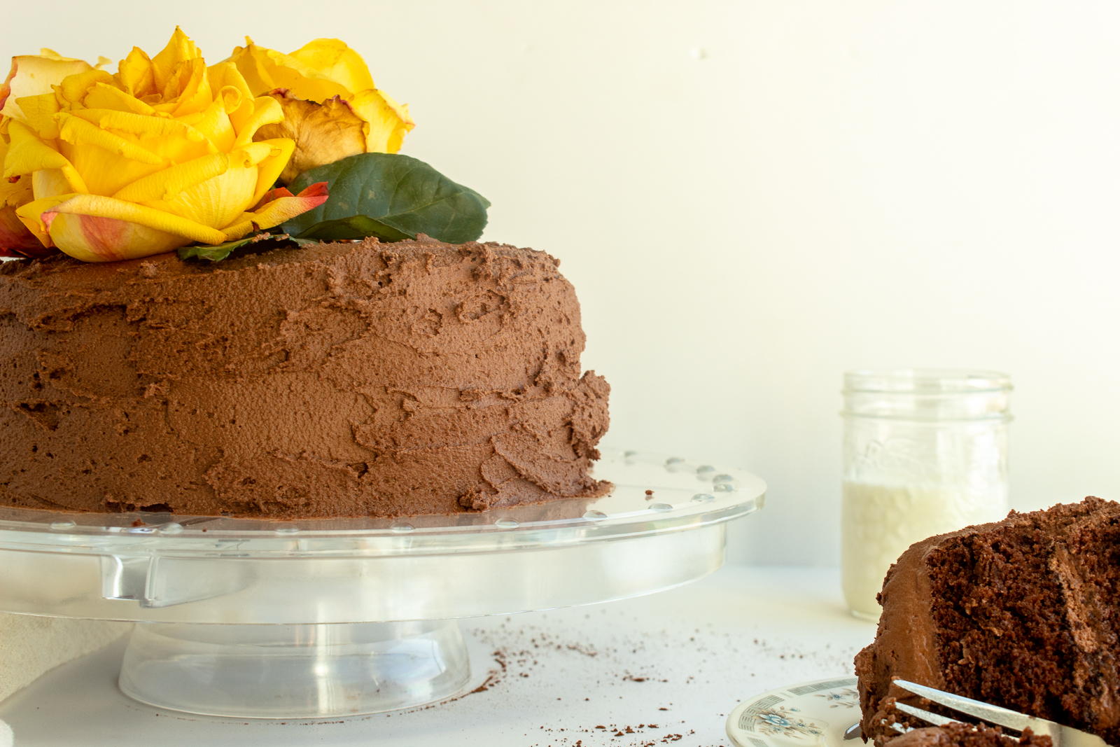 Chocolate layer cake on clear cake stand straight on shot.