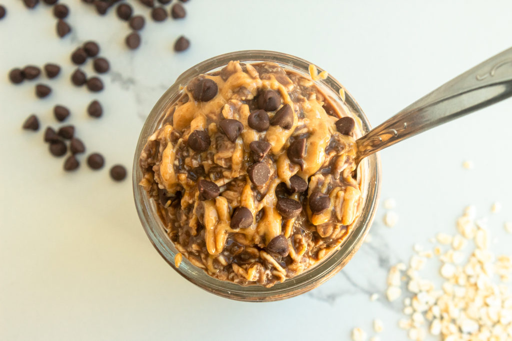 Chocolate Peanut butter overnight oats in mason jar with spoon overhead shot.