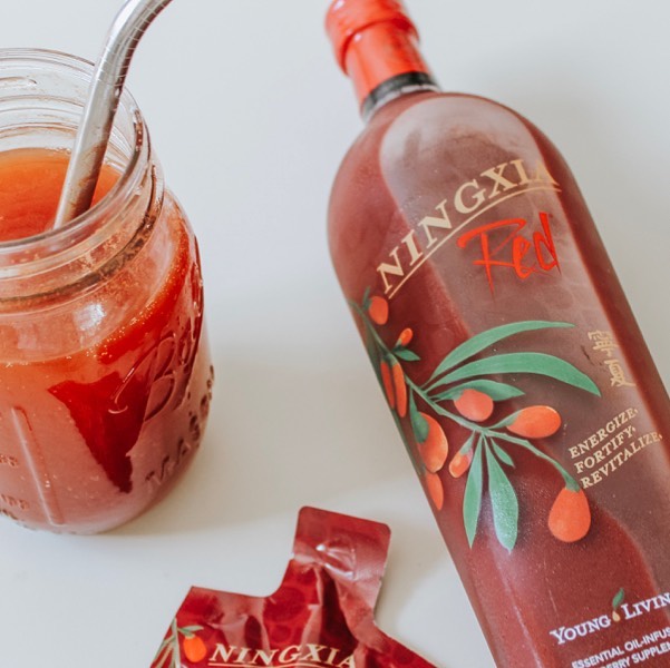 Bottle of Ningxia Red next to Ningxia pouch and mason jar glass with straw filled with Ningxia.