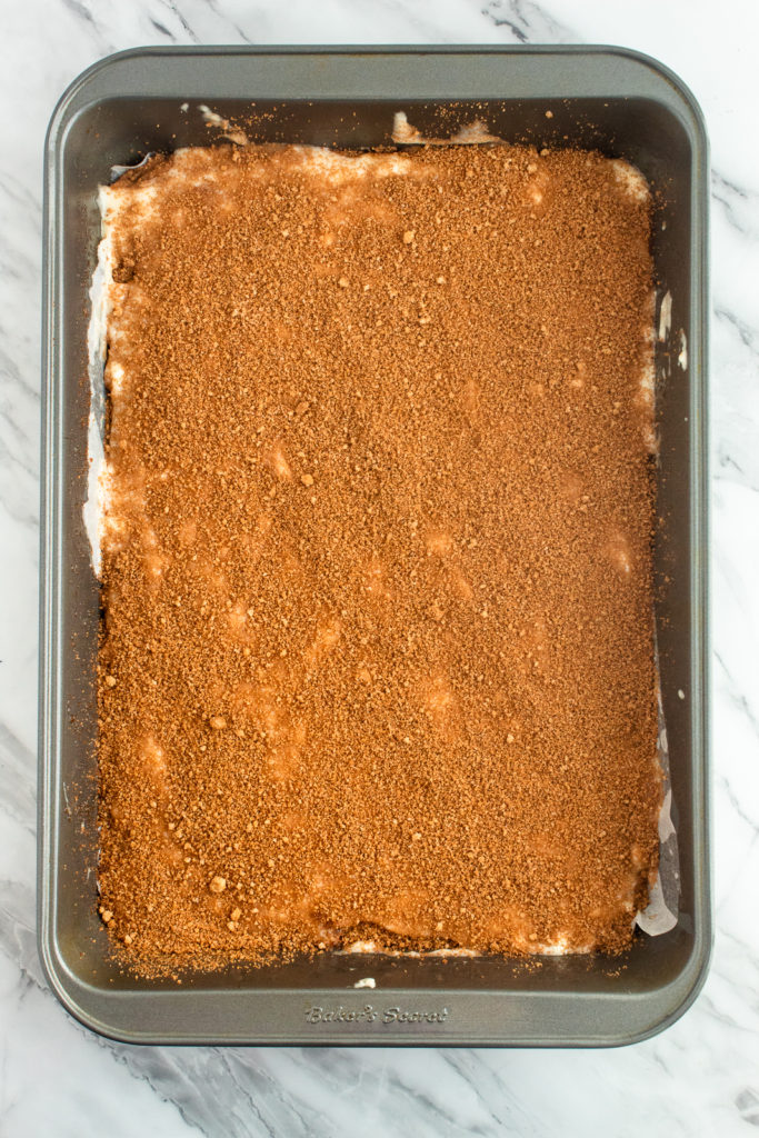 Coffee cake batter with cinnamon sugar sprinkled on top in sheet pan overhead shot.