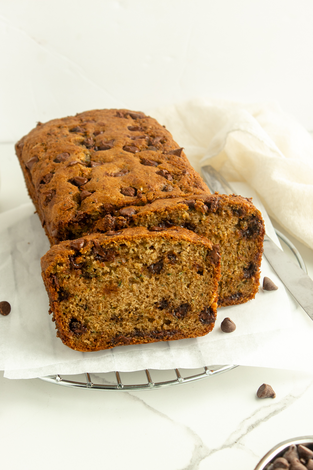 Chocolate chip zucchini bread on wire rack with parchment paper angled shot.