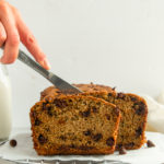 Easy Chocolate chip zucchini bread straight on shot with hand cutting into it with knife.