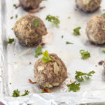 Easy basic meatballs cooked spaced out on tin foil line baking sheet angled shot.