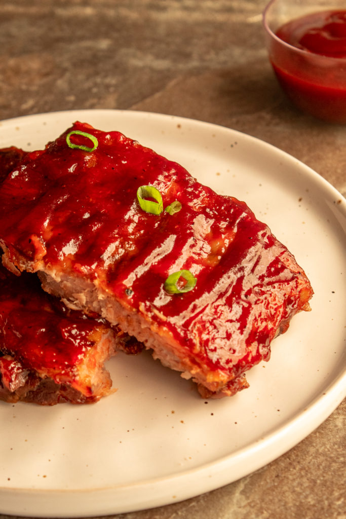 Slow Cooker BBQ Pork Ribs angled shot on plate with green onions.