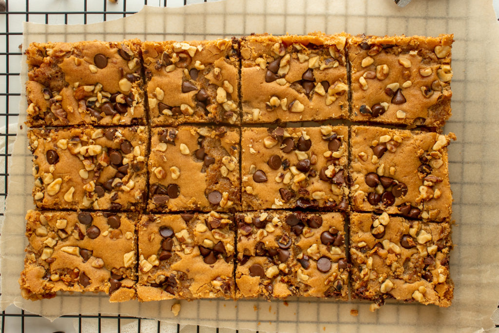 Chewy Nut Blondies cut into squares over parchment paper over wire rack overhead shot.