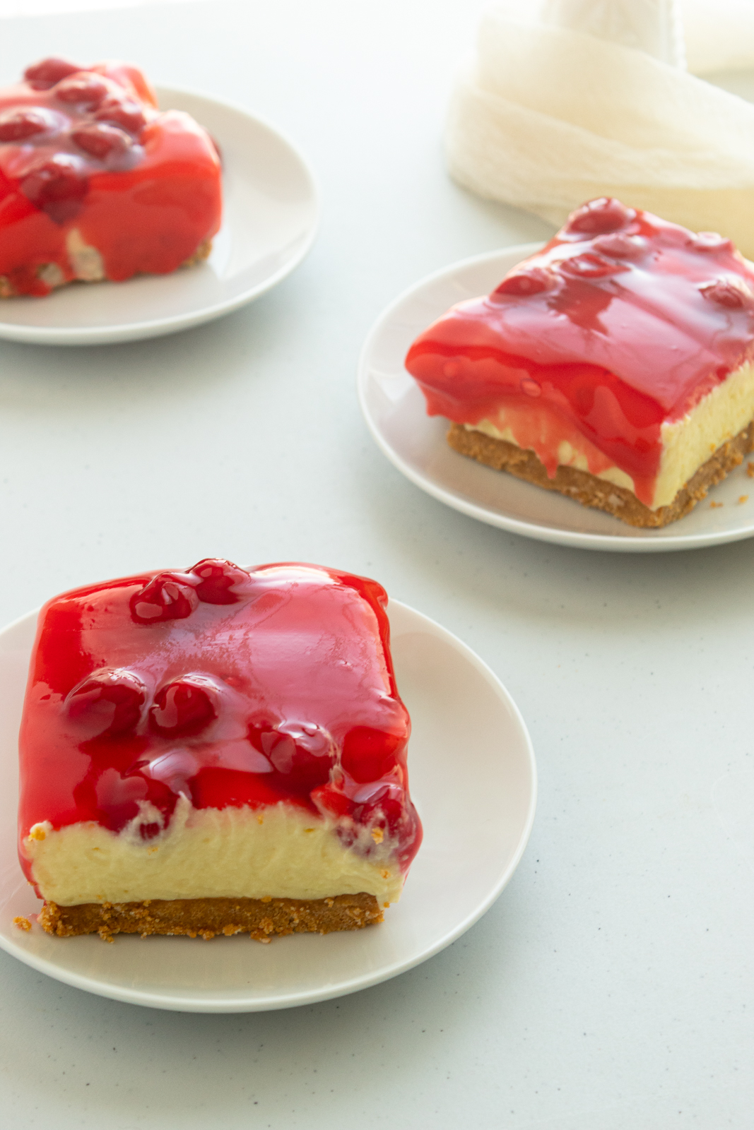 No-bake lemon cheesecake with pie filling on 3 plates angled shot.