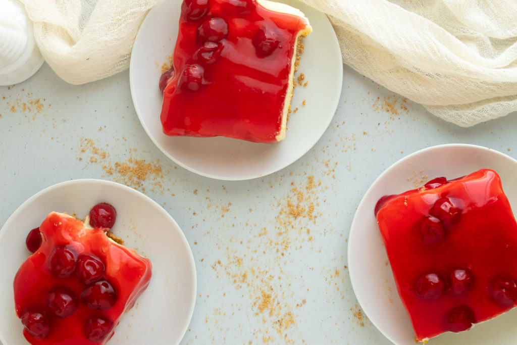 Overhead shot of No-bake lemon cheesecake with pie filling on 3 plates.