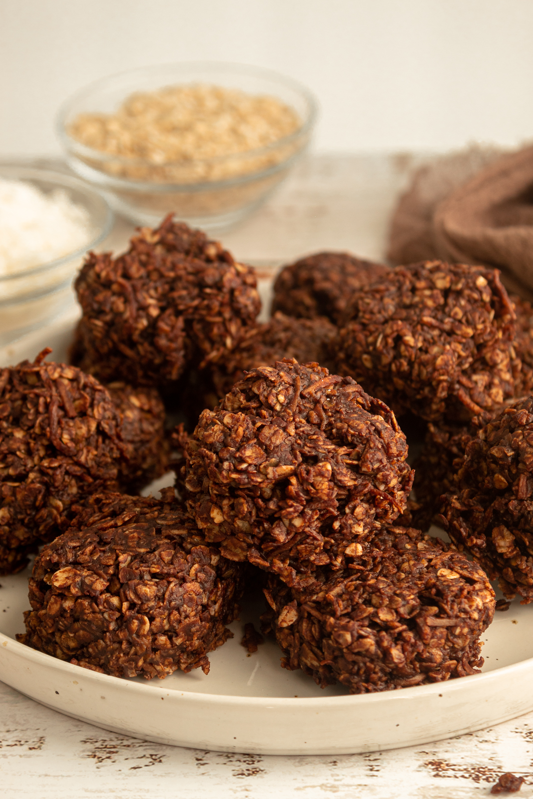 Angled shot fo Chocolate Drops on plate with oats and shredded coconut in background with brown cheesecloth.