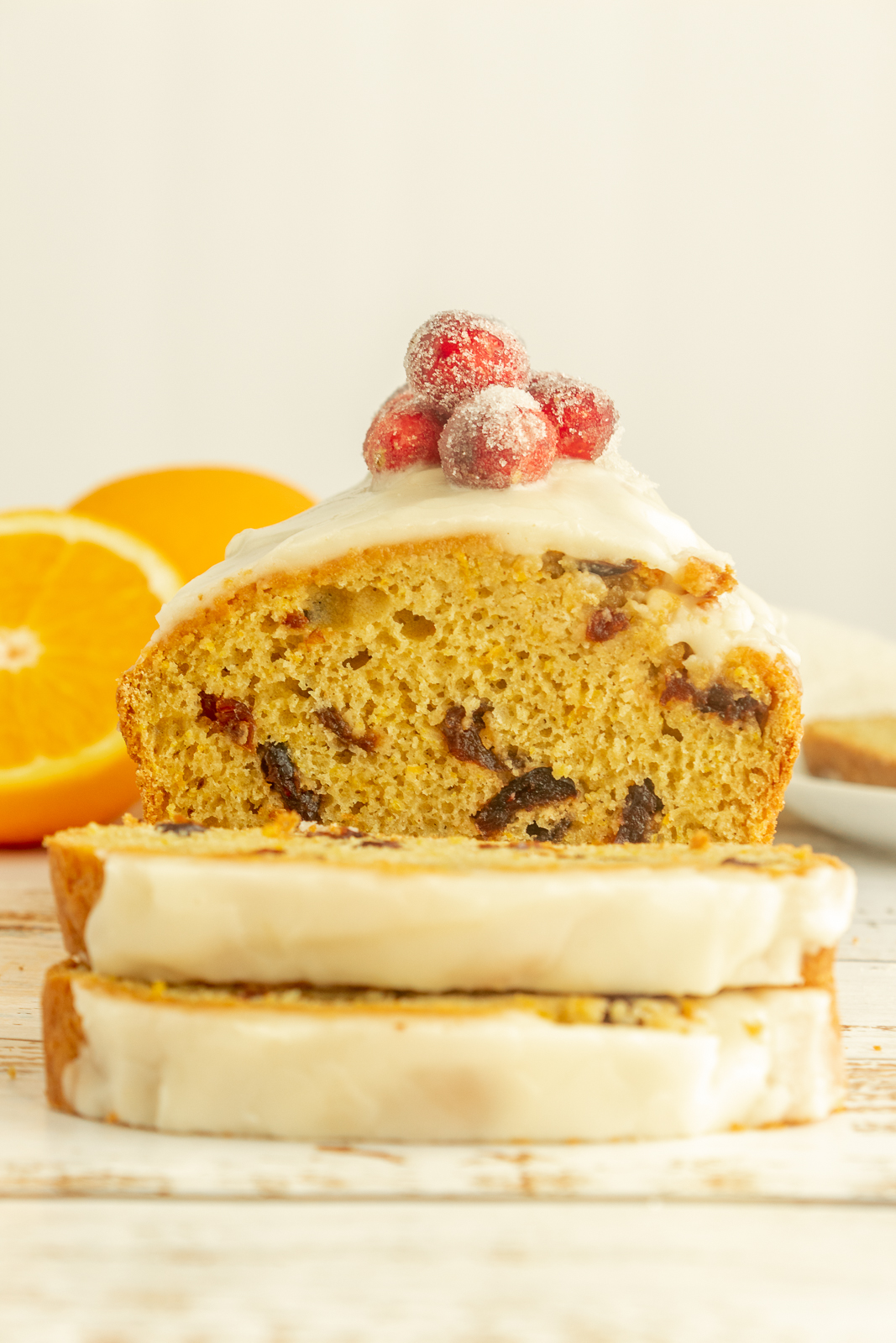 Gluten-free orange cranberry bread straight on shot with two slices in front.