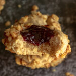 thumbprint cookie with jam and walnuts close up shot with bite overhead.