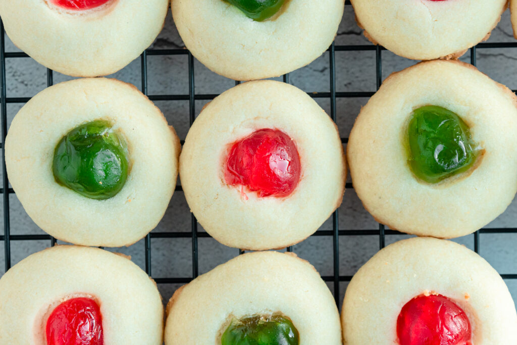 Overhead shot of Whipped shortbread with glaze cherries on top on wire rack.