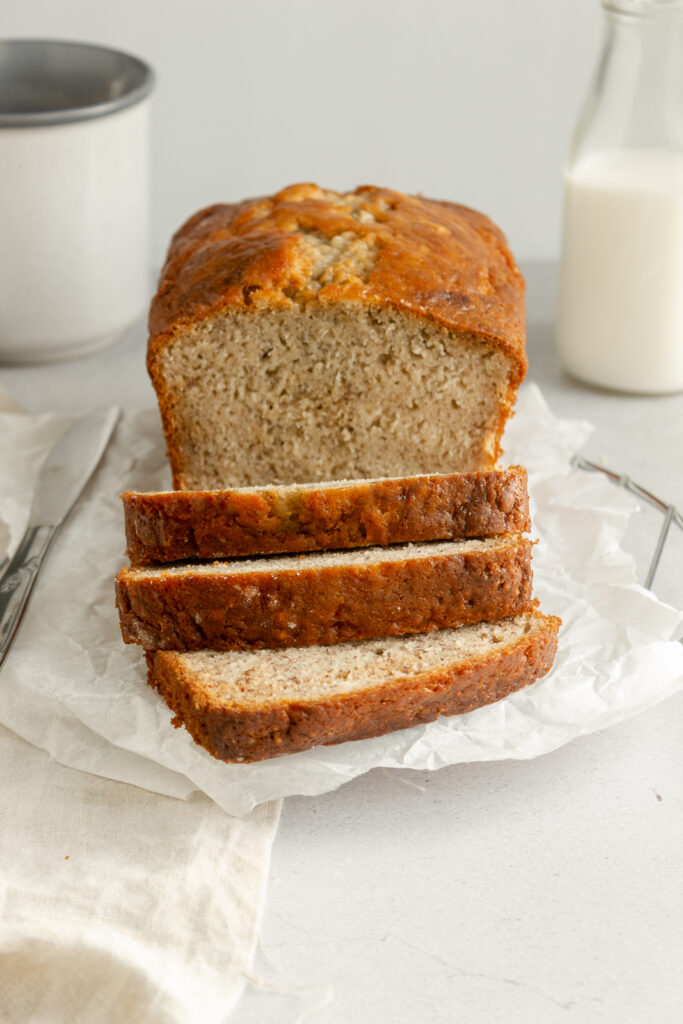 Angled shot of Easy Moist Banana bread on wire rack and butter knife.