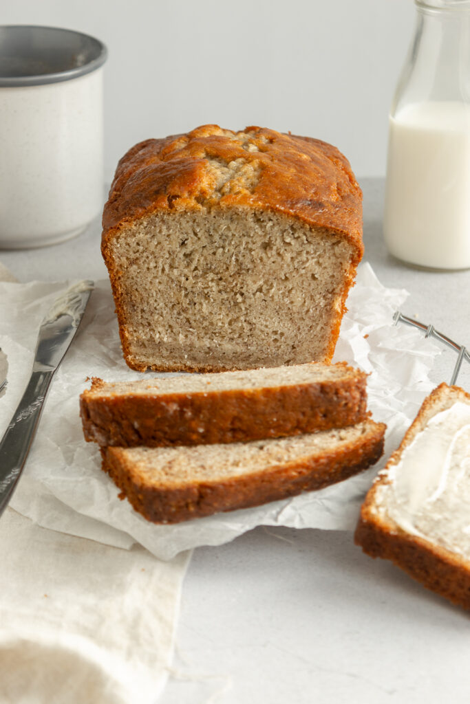 Angled shot of Easy Moist Banana bread on wire rack and butter knife.