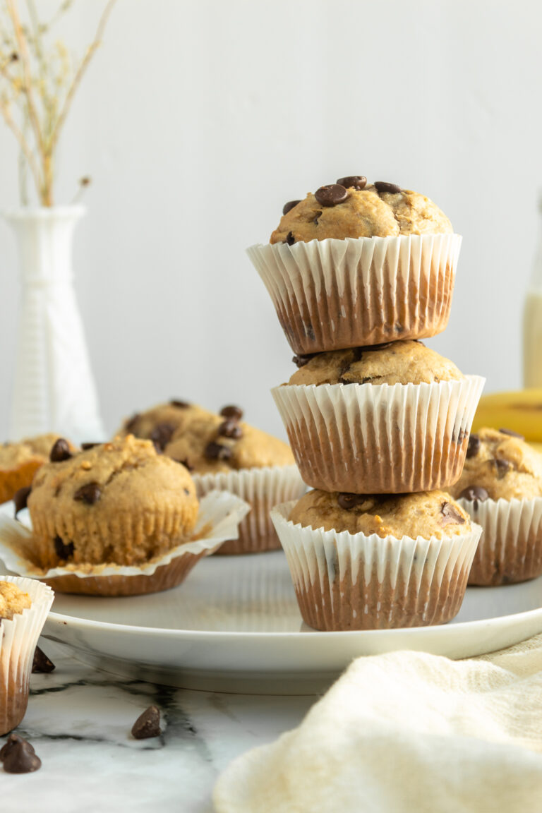 Peanut butter chocolate chip muffins 3 stacked on top of each other with muffins surrounding.