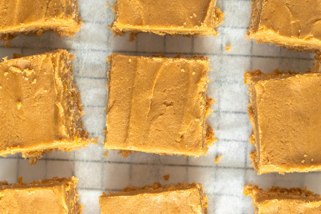 Overhead shot of Peanut butter squares on parchment on wire rack.