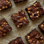 Overhead shot of classic brownies cut up on parchment paper.