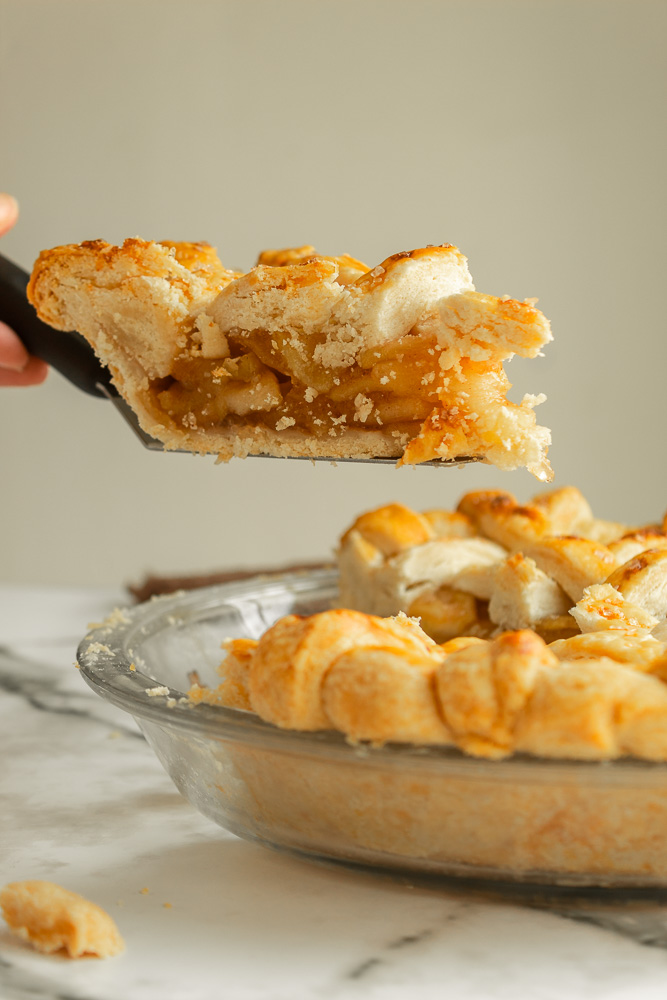 Straight on shot of slice of Apple pie being served in midair.