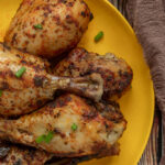 Overhead shot of Easy Slow Cooker chicken drumsticks on yellow plate with brown linen.