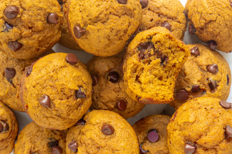 Overhead shutoff Pumpkin chocolate chip muffins piled with one bite taken out.