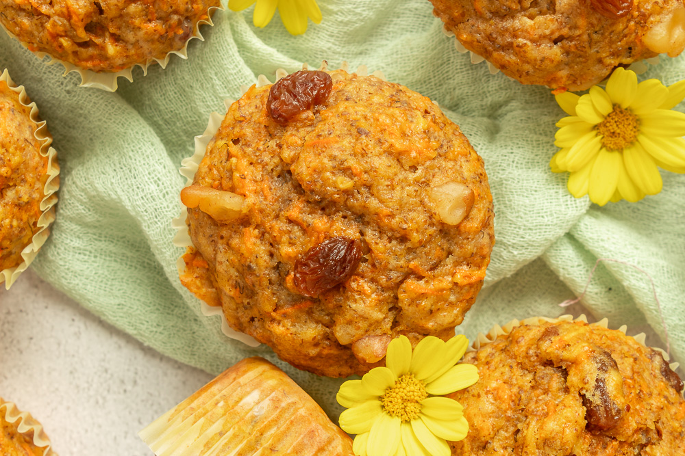 Overhead shot of Loaded Morning Glory Muffins close up with yellow flowers and green linen.