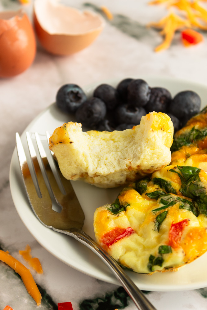 Angled shot of Easy Breakfast Egg muffins on plate with fork and bite shot.