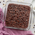 Overhead shot of Brownie Baked Oatmeal with purple linen and forks with plates on the side.