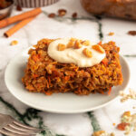 Angled shot of Easy Baked Carrot Oatmeal on plate with cream cheese glaze and walnuts on top.